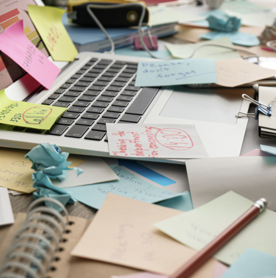 Image of a cluttered workspace with sticky notes and papers scattered around a laptop, symbolizing disorganized business operations and the need for streamlined systems to achieve sustainable growth.